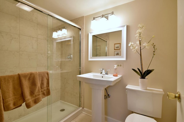 bathroom featuring a shower stall, toilet, and a sink