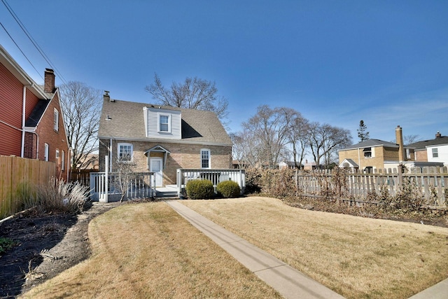 bungalow featuring a wooden deck, brick siding, a front yard, and fence