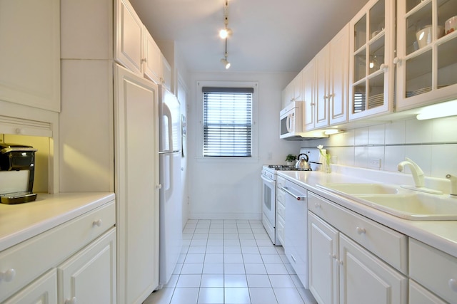 kitchen featuring white appliances, light tile patterned flooring, a sink, glass insert cabinets, and backsplash