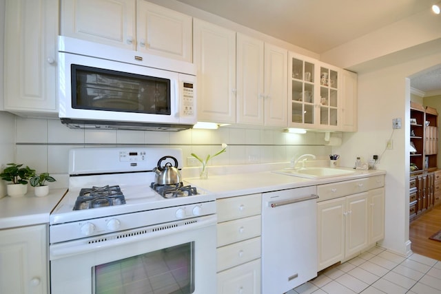 kitchen with tasteful backsplash, white appliances, white cabinetry, and a sink