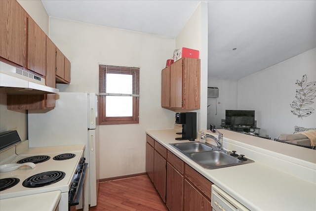 kitchen with light wood finished floors, a sink, under cabinet range hood, white appliances, and light countertops