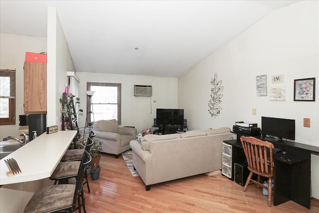 living area featuring lofted ceiling, an AC wall unit, and light wood-style flooring