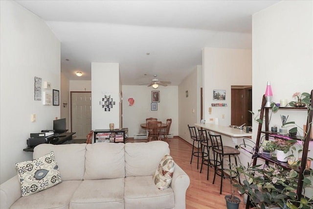 living room featuring ceiling fan, a baseboard heating unit, and wood finished floors