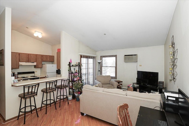 living area with lofted ceiling, light wood-type flooring, and a wall mounted AC