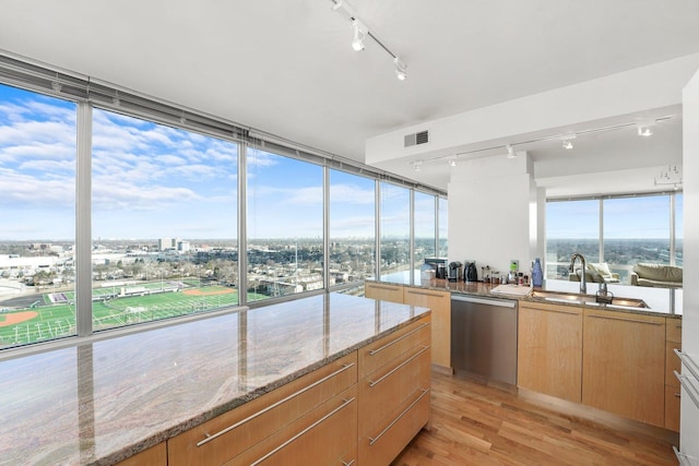 kitchen featuring visible vents, modern cabinets, light wood-style floors, light stone countertops, and dishwasher