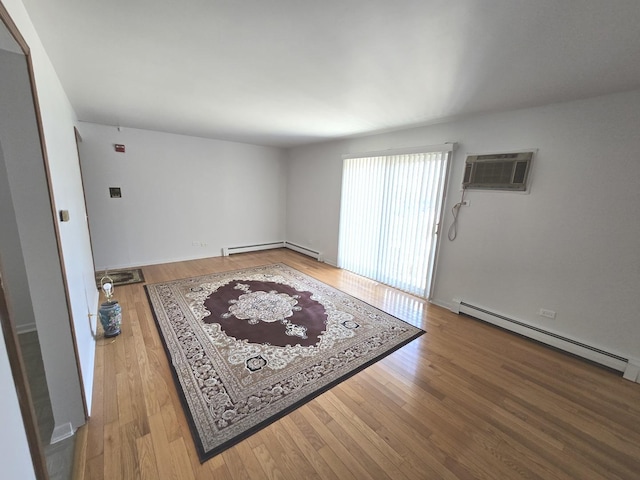 interior space with a baseboard heating unit, wood finished floors, baseboard heating, and a wall mounted AC