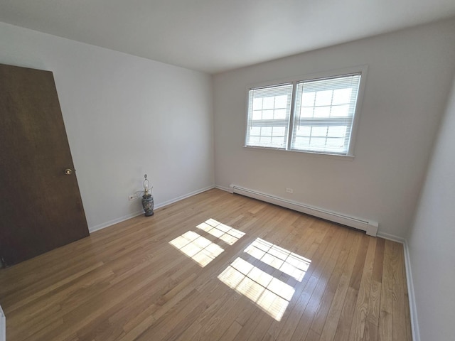 unfurnished room with light wood-style flooring, baseboards, and a baseboard radiator