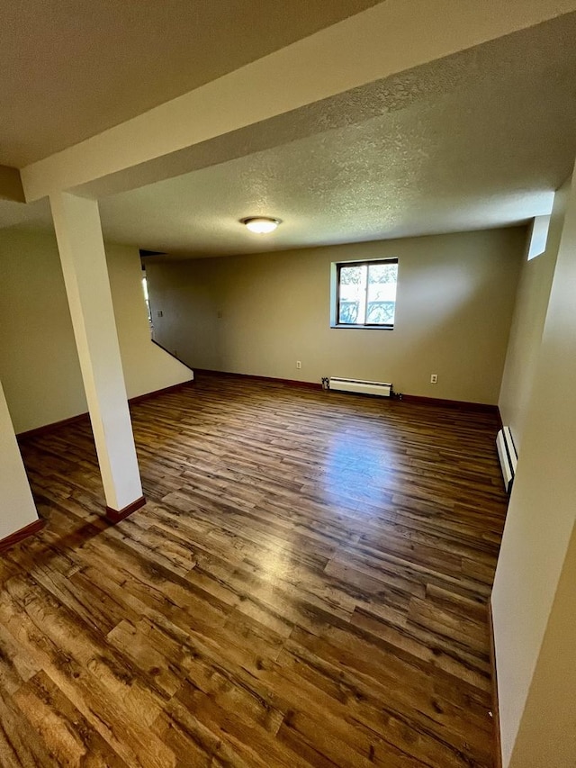 below grade area with a textured ceiling, wood finished floors, and a baseboard radiator