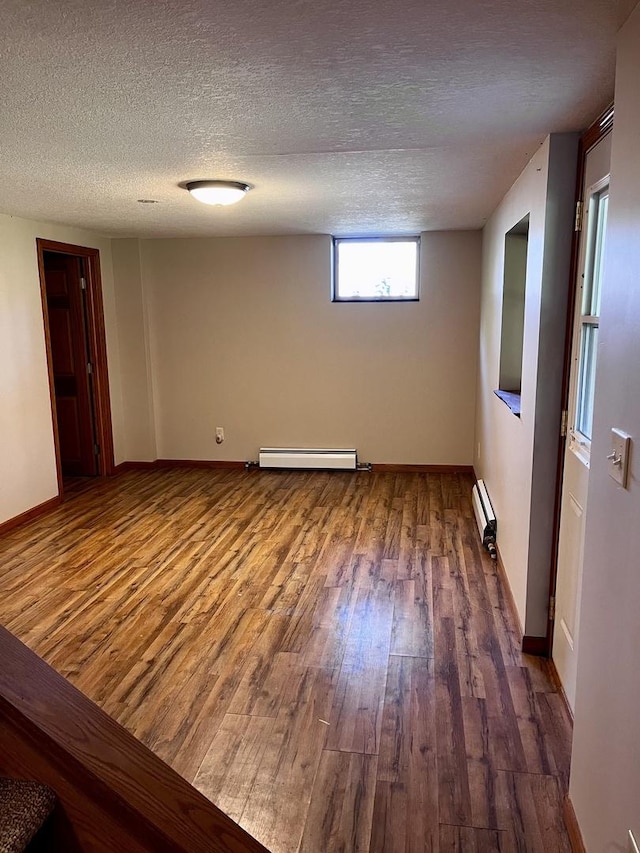 unfurnished room with a baseboard heating unit, baseboards, baseboard heating, wood finished floors, and a textured ceiling