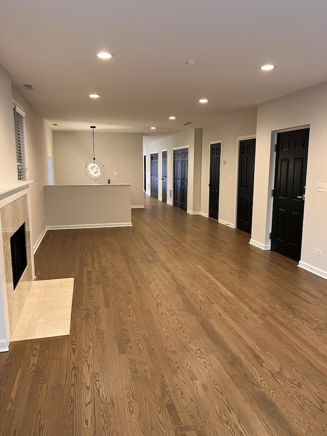 unfurnished living room with visible vents, wood finished floors, recessed lighting, baseboards, and a tile fireplace