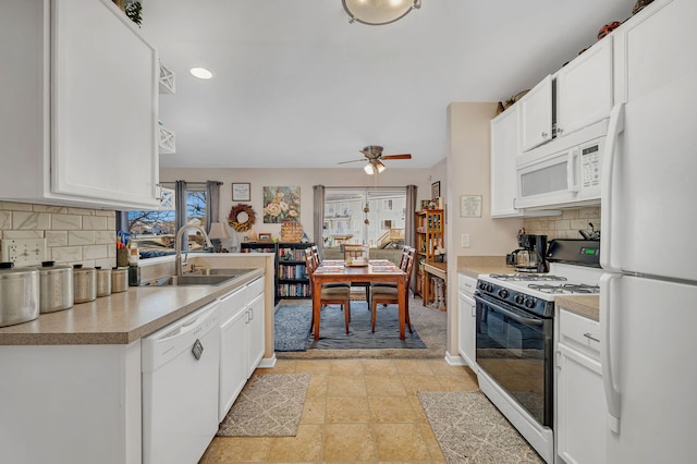 kitchen featuring a sink, decorative backsplash, white appliances, and light countertops