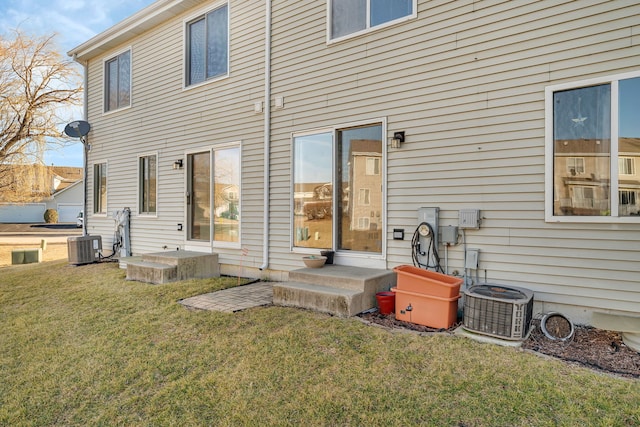 back of house with entry steps, cooling unit, and a yard