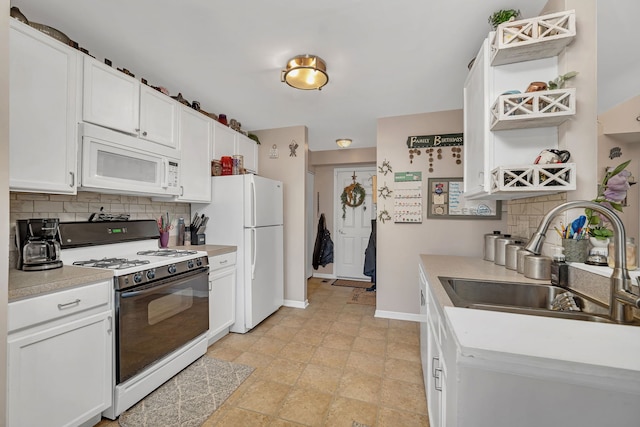 kitchen featuring white appliances, baseboards, a sink, decorative backsplash, and white cabinetry