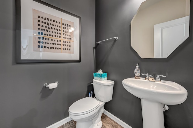 half bathroom featuring a sink, baseboards, and toilet