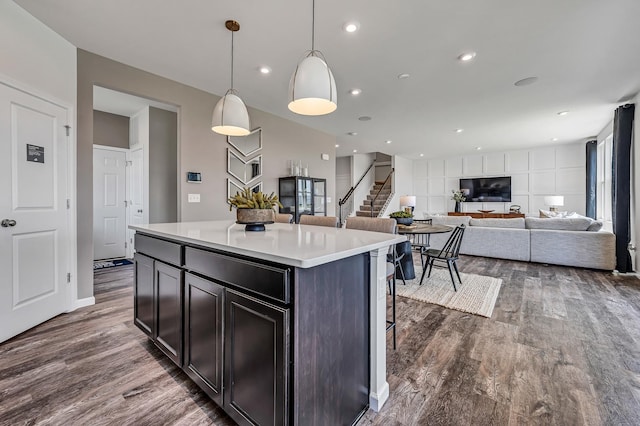 kitchen featuring dark wood-style floors, a center island, light countertops, and a breakfast bar