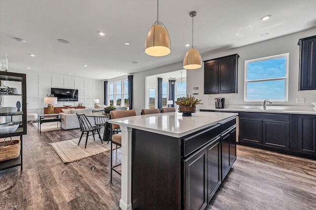 kitchen featuring a breakfast bar, a center island, light countertops, and dark wood-type flooring