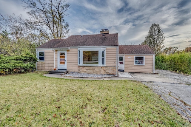 view of front of house with a front lawn, roof with shingles, and a chimney