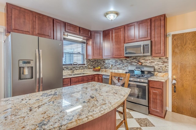 kitchen with light stone counters, backsplash, appliances with stainless steel finishes, and a sink