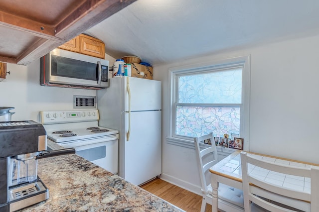 kitchen featuring baseboards, light countertops, vaulted ceiling, light wood-style flooring, and white appliances