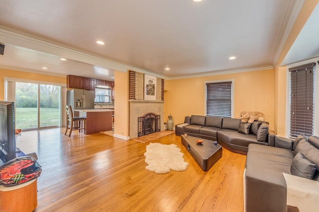 living area with recessed lighting, a fireplace, light wood-type flooring, and crown molding