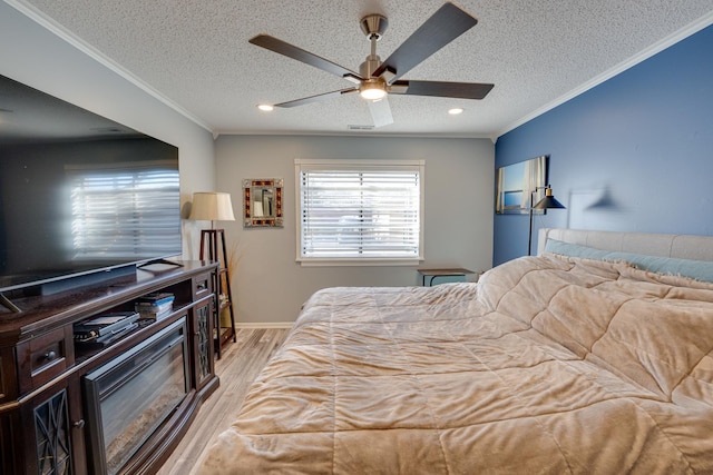 bedroom featuring a textured ceiling, a ceiling fan, light wood-style floors, and ornamental molding