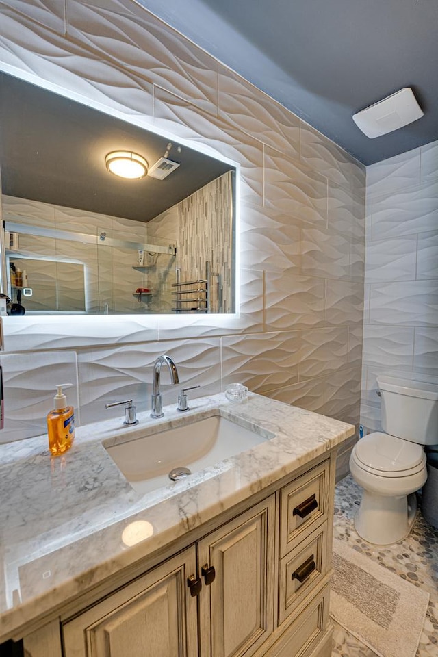 full bathroom with visible vents, toilet, tile walls, and vanity