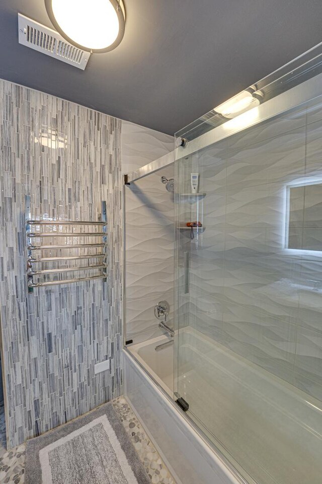 full bath featuring visible vents and shower / bath combination with glass door