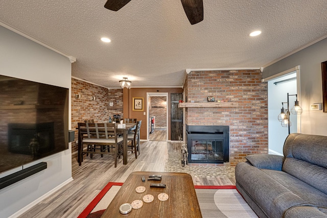 living room featuring a brick fireplace, wood finished floors, and crown molding