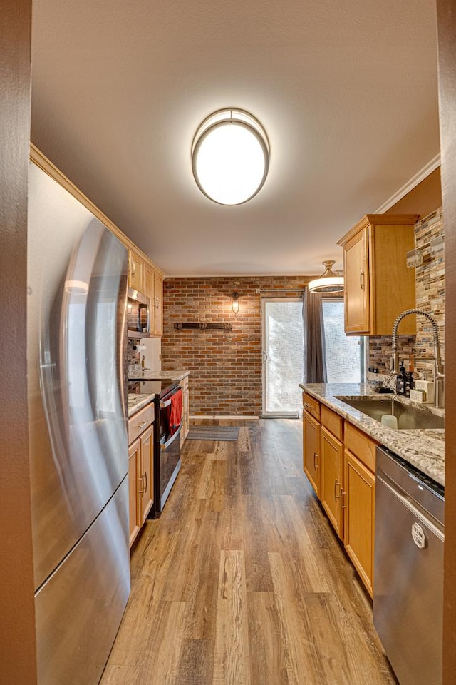 kitchen with a sink, appliances with stainless steel finishes, wood finished floors, and crown molding