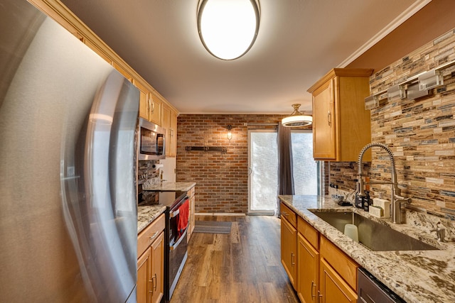 kitchen featuring a sink, light stone counters, backsplash, stainless steel appliances, and dark wood-style flooring