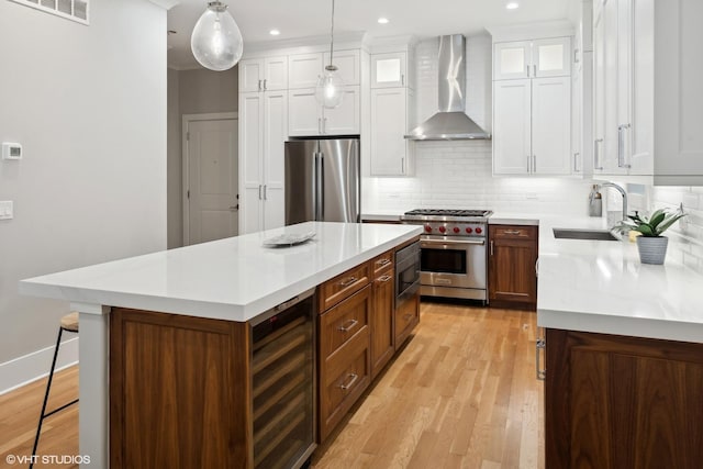 kitchen with visible vents, a sink, wine cooler, appliances with stainless steel finishes, and wall chimney exhaust hood