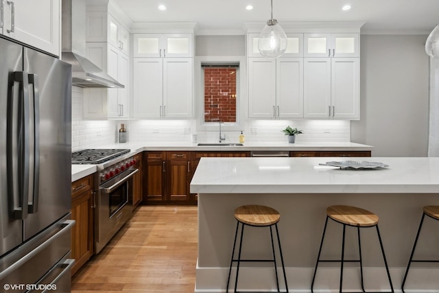 kitchen featuring a sink, stainless steel appliances, a kitchen breakfast bar, and wall chimney exhaust hood