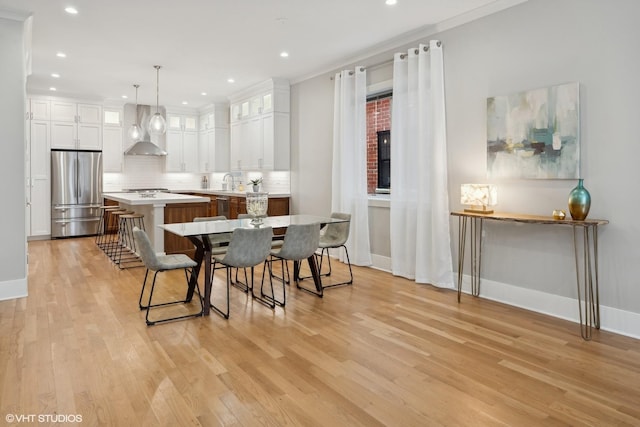 kitchen featuring a kitchen island, stainless steel appliances, white cabinetry, wall chimney exhaust hood, and backsplash