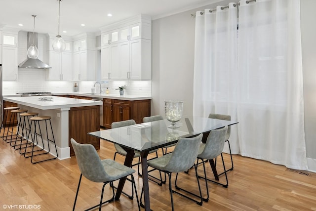 dining space featuring recessed lighting, light wood-type flooring, and crown molding