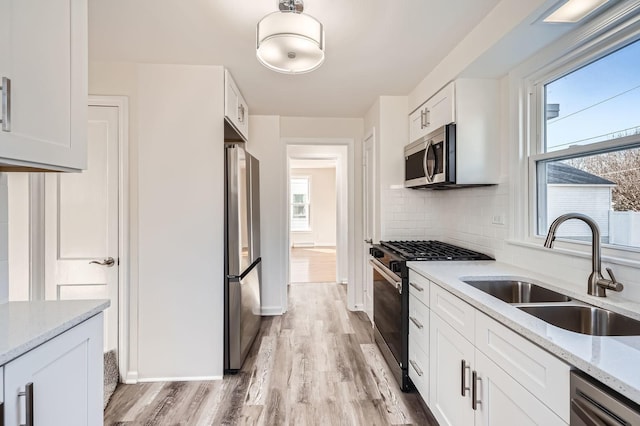 kitchen featuring a sink, stainless steel appliances, backsplash, and white cabinetry