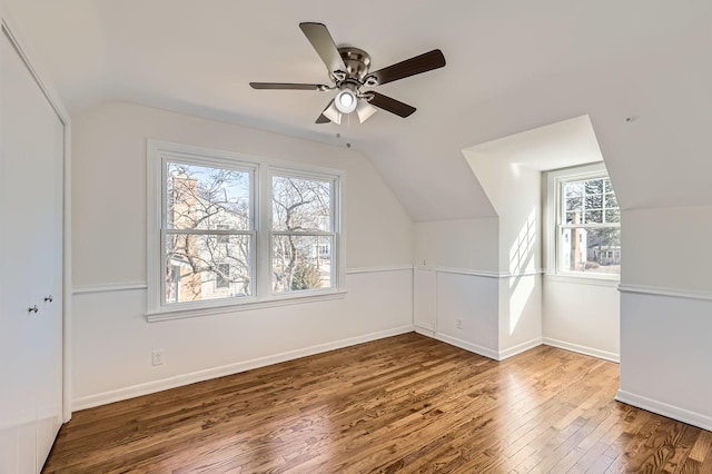 additional living space featuring hardwood / wood-style flooring, a ceiling fan, baseboards, and vaulted ceiling