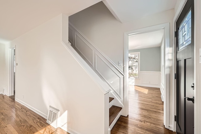 interior space with stairway, a decorative wall, a wainscoted wall, and wood finished floors