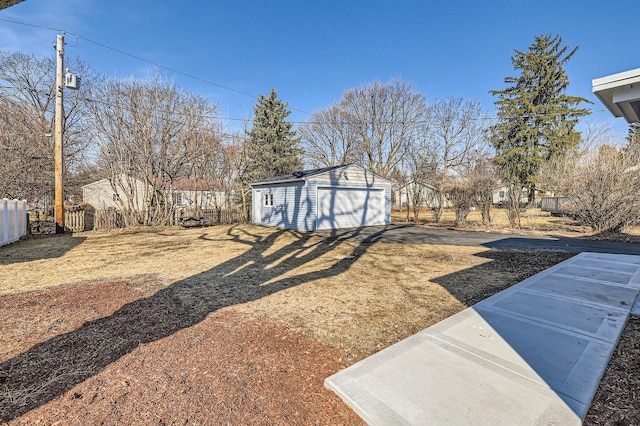 view of yard featuring a detached garage, an outbuilding, and fence