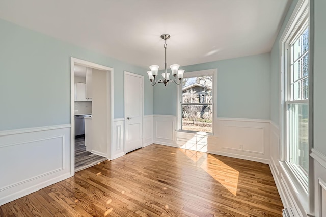 unfurnished dining area featuring wood finished floors, a wealth of natural light, and a chandelier