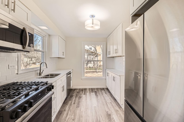 kitchen with a sink, decorative backsplash, light countertops, white cabinets, and stainless steel appliances