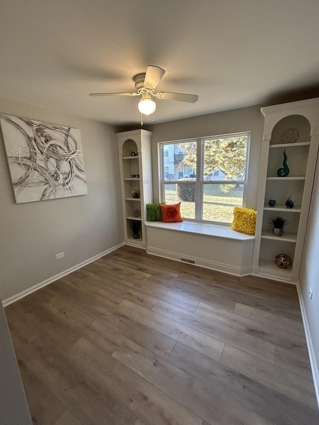 interior space with visible vents, baseboards, a ceiling fan, and wood finished floors