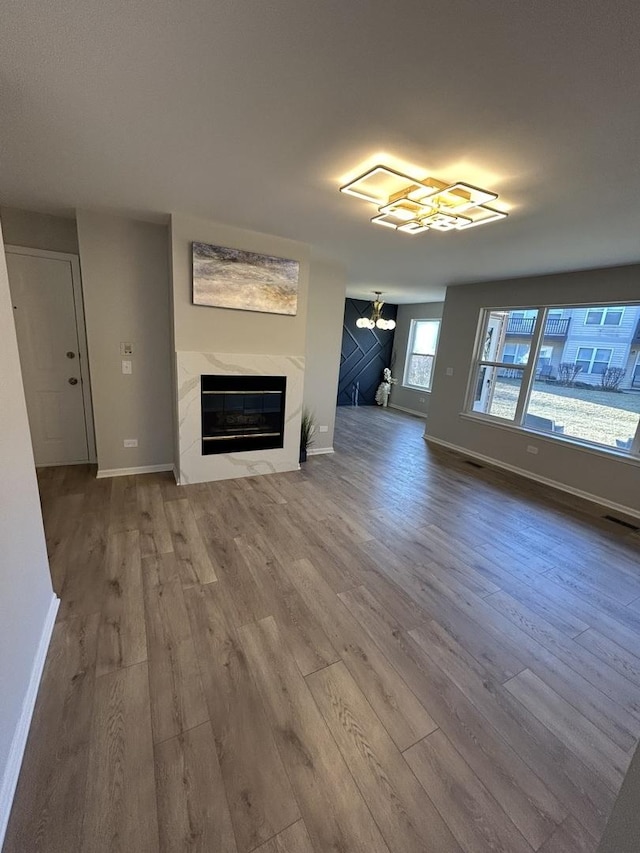 unfurnished living room with visible vents, baseboards, wood finished floors, and a high end fireplace