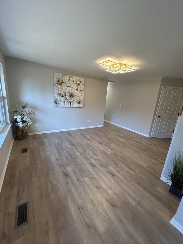 unfurnished living room with visible vents, baseboards, and wood finished floors