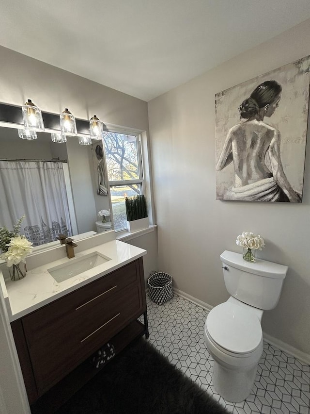 bathroom with tile patterned floors, baseboards, toilet, and vanity