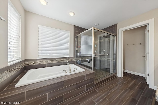 bathroom featuring a bath, baseboards, a stall shower, and wood finish floors