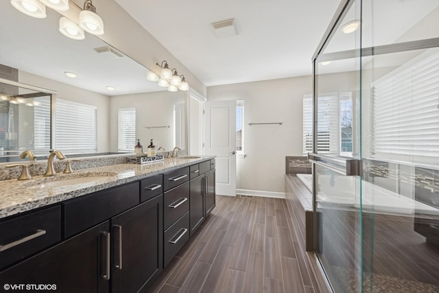 bathroom with a sink, visible vents, a garden tub, and double vanity