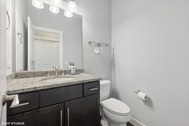 bathroom featuring toilet, vanity, and baseboards