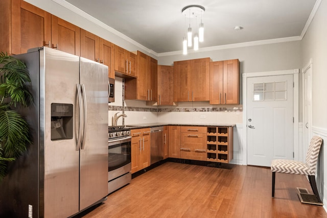 kitchen featuring brown cabinetry, wood finished floors, ornamental molding, appliances with stainless steel finishes, and backsplash