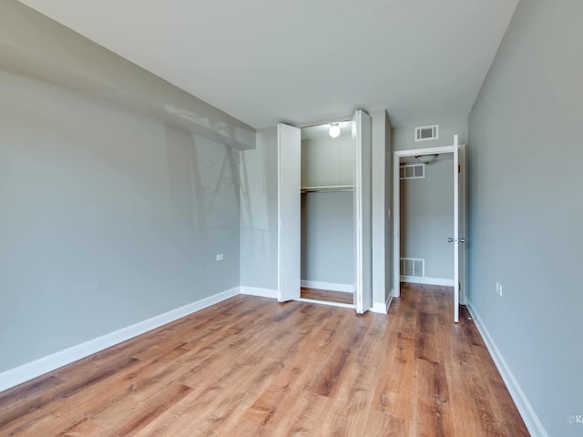 unfurnished bedroom featuring visible vents, light wood-style floors, and a closet