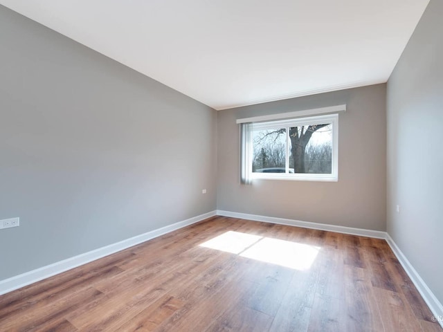 spare room with baseboards and wood finished floors